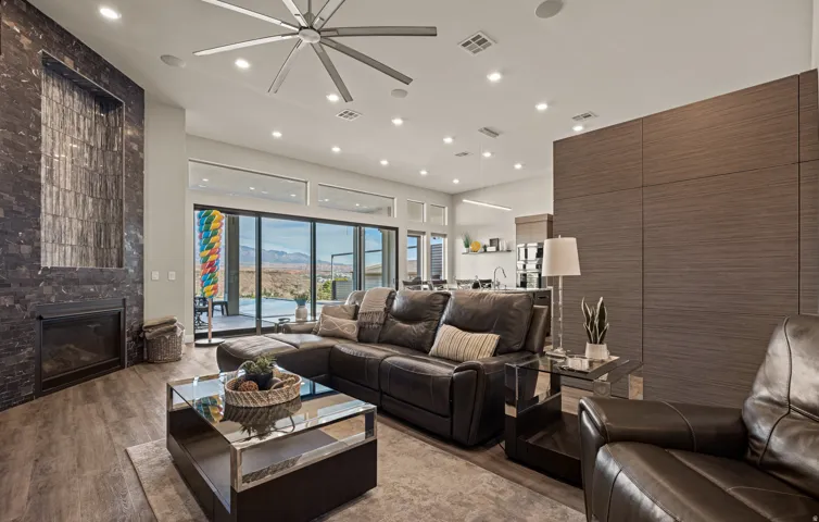 Sophisticated living room showcasing a black leather sectional, glass-top coffee table, and wood-finish flooring throughout