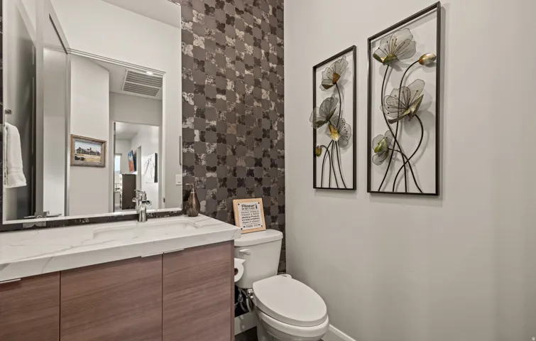 Floating wood-finish vanity with an integrated rectangular sink, wall-mounted mirror, and decorative tiled accent wall