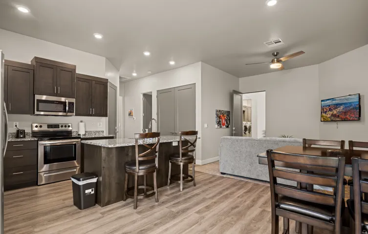 Modern kitchen featuring dark wood cabinetry, stainless steel appliances, granite countertops, and a central island with a breakfast bar