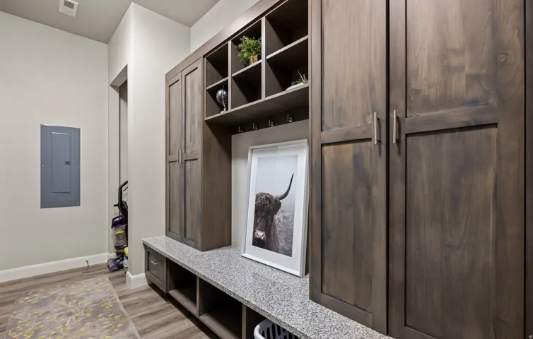 Built-in cabinetry with a dark wood finish, a speckled countertop, integrated shelving, and hooks for storage