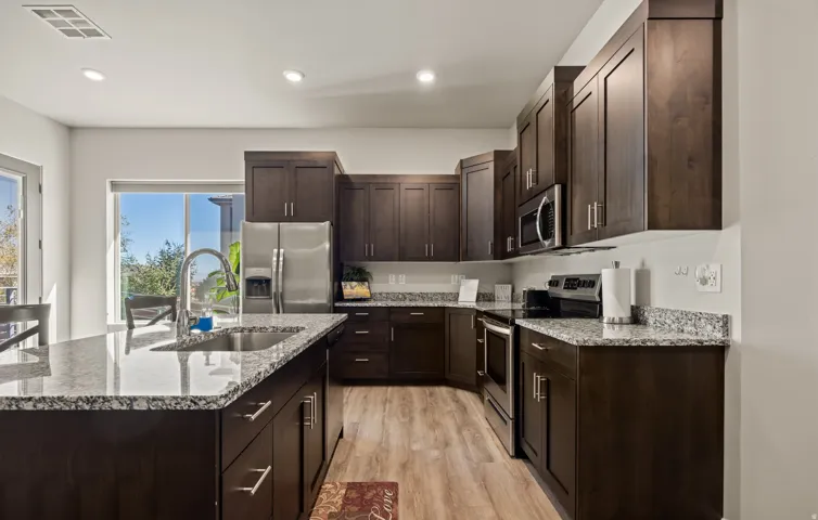 Modern MOTHER-IN-LAW KITCHEN featuring dark wood cabinetry, stainless steel appliances, and quartz countertops with mosaic tile backsplash