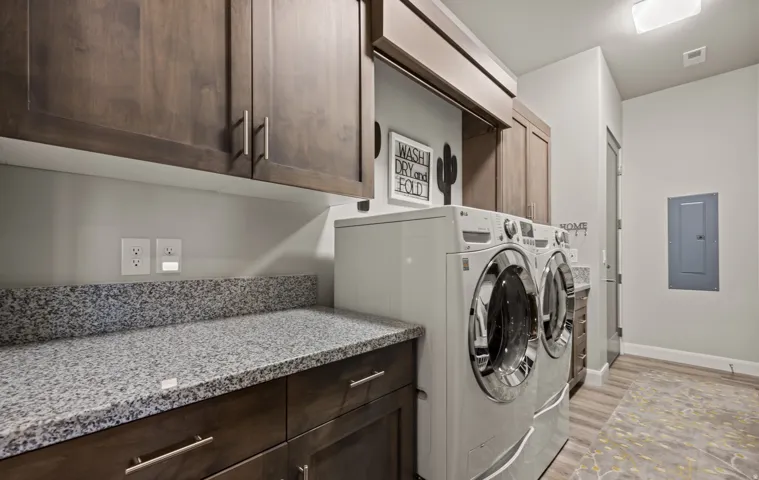 Laundry room with wood-finish cabinetry, light-toned walls, a granite-finish countertop, and wood-finish flooring