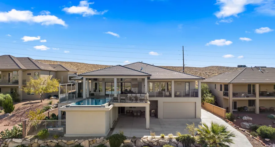 Multi-level exterior with a private swimming pool, expansive covered patio, glass-panel railings, and an integrated two-car garage