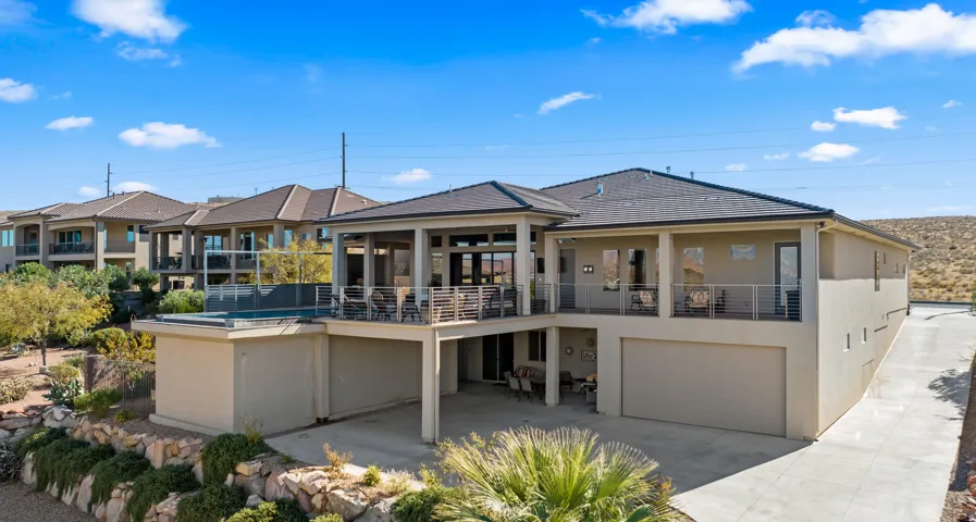 Stucco exterior with multiple covered balconies, an attached garage, a flat roof section with an integrated pool, and desert landscaping