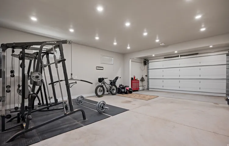 Recessed lighting illuminates the concrete flooring and garage door