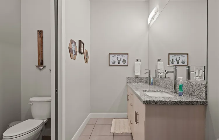 Dual vanity with polished chrome faucets, granite-look countertop, and wood-finish cabinetry