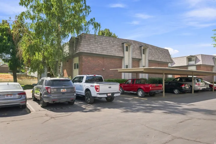 Brick and siding exterior with dormer windows and a covered parking structure