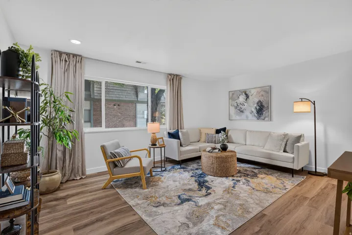 Recessed lighting, wood-finish flooring, white walls, and a large window with privacy curtains