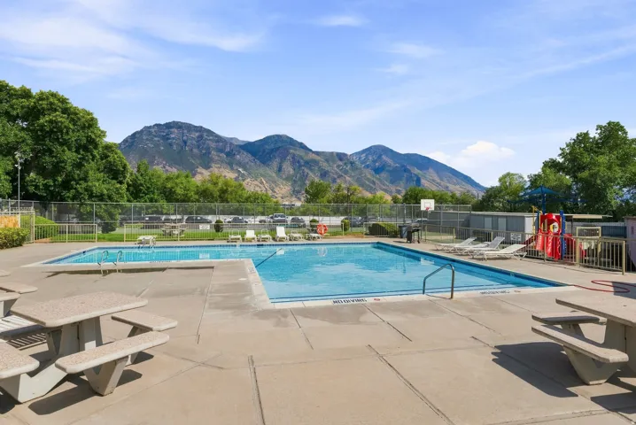 Community swimming pool with concrete decking, surrounding trees, and mountain scenery