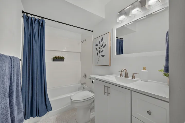 White shaker-style vanity with a single basin sink and brushed nickel fixtures