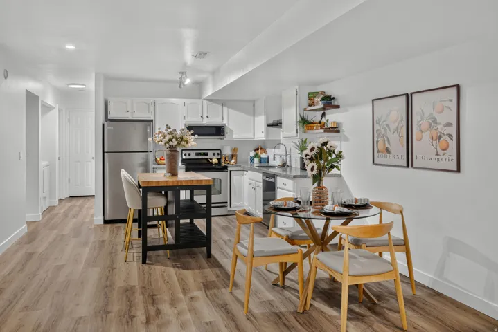 Kitchen with white cabinetry, stainless steel appliances, and wood-finish flooring