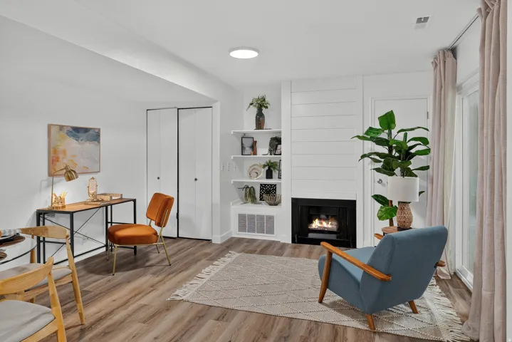 Wood-finish flooring throughout, a built-in fireplace with a shiplap surround, integrated shelving, and bi-fold closet doors