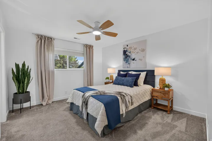 Carpeted room with a ceiling fan, a window with curtains, and white walls