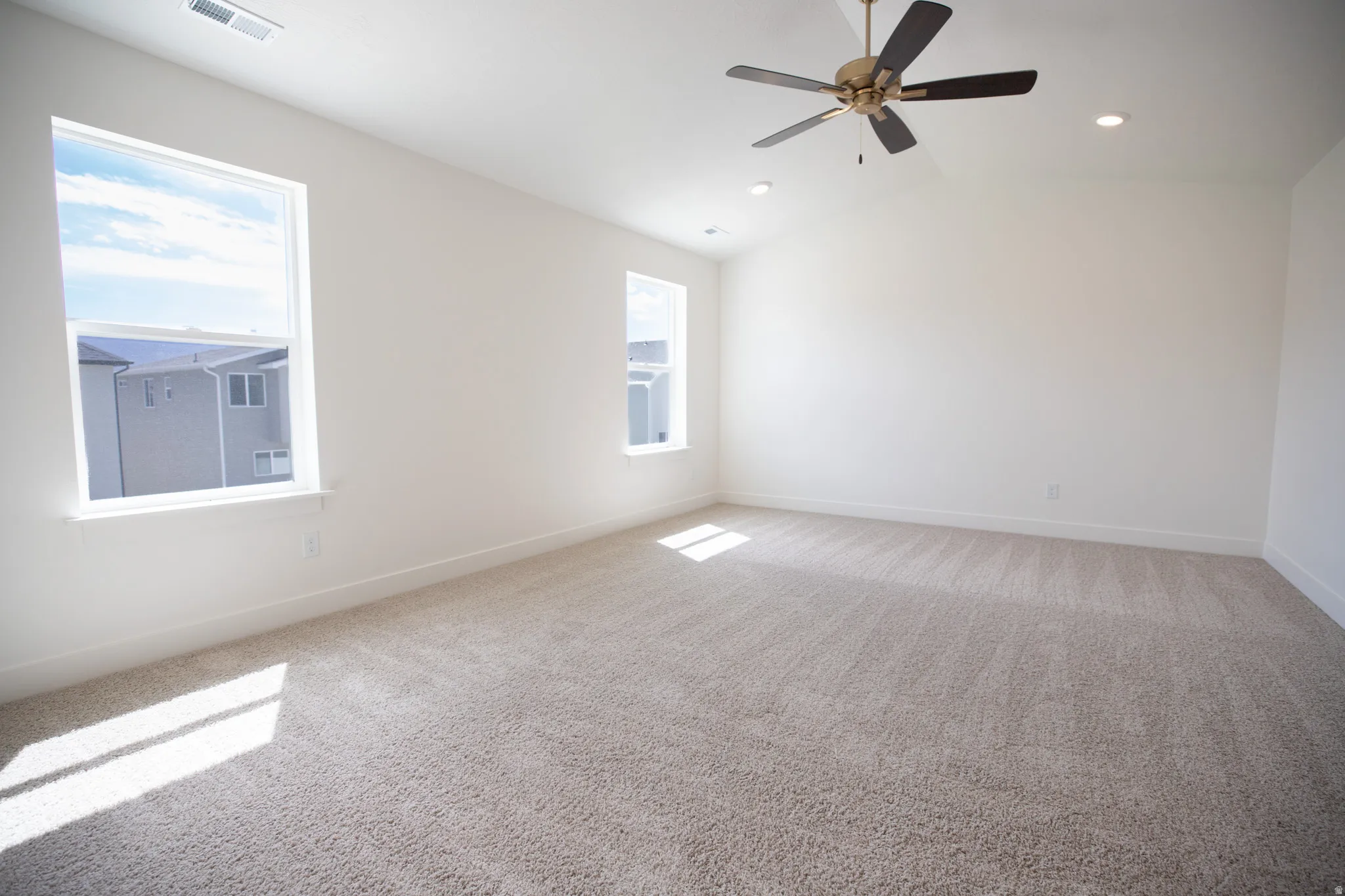 Primary bedroom with vaulted ceiling and ceiling fan.