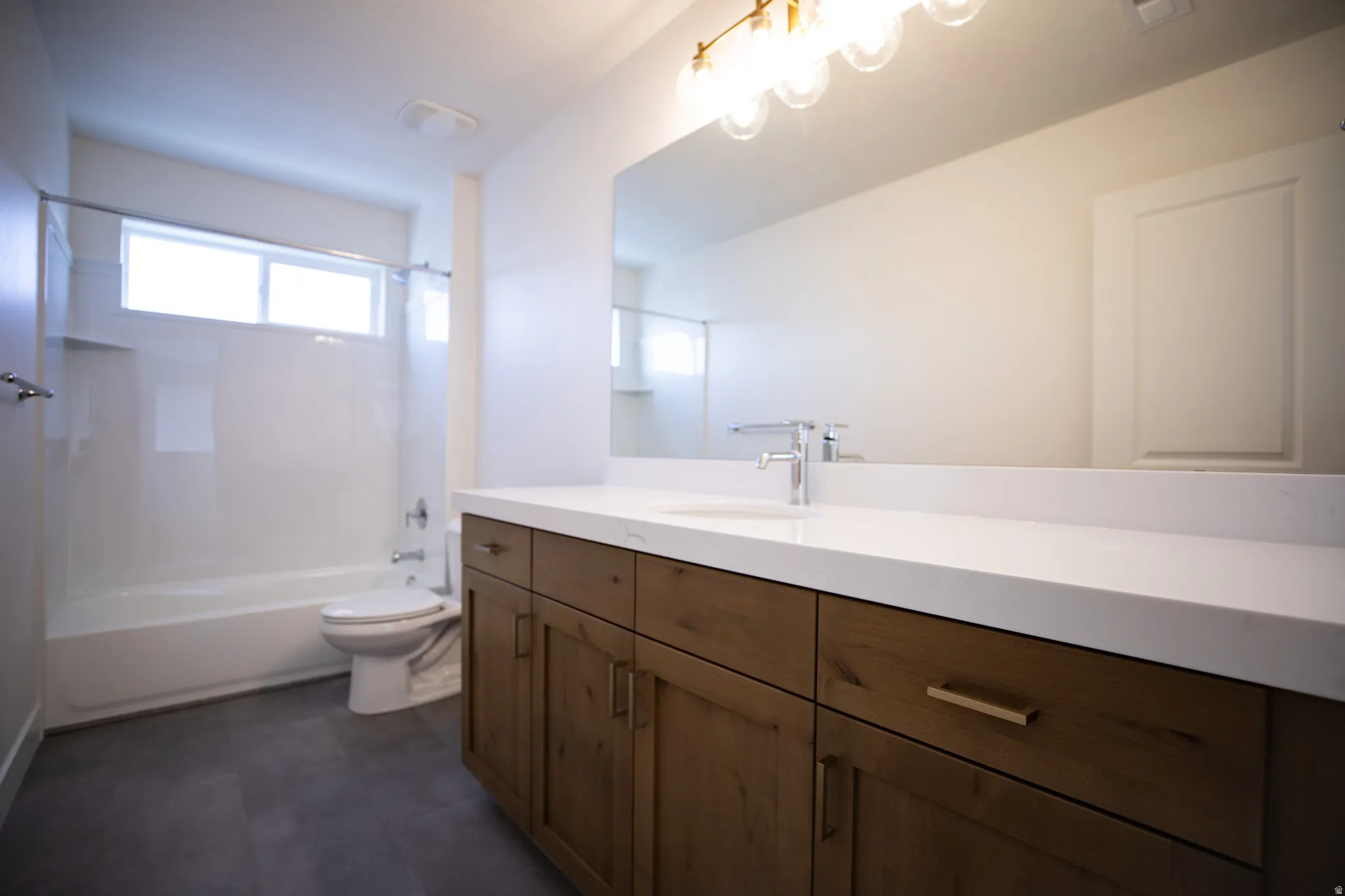 Full secondary bath with stained wood cabinets, extra-long vanity and quartz slab countertops.