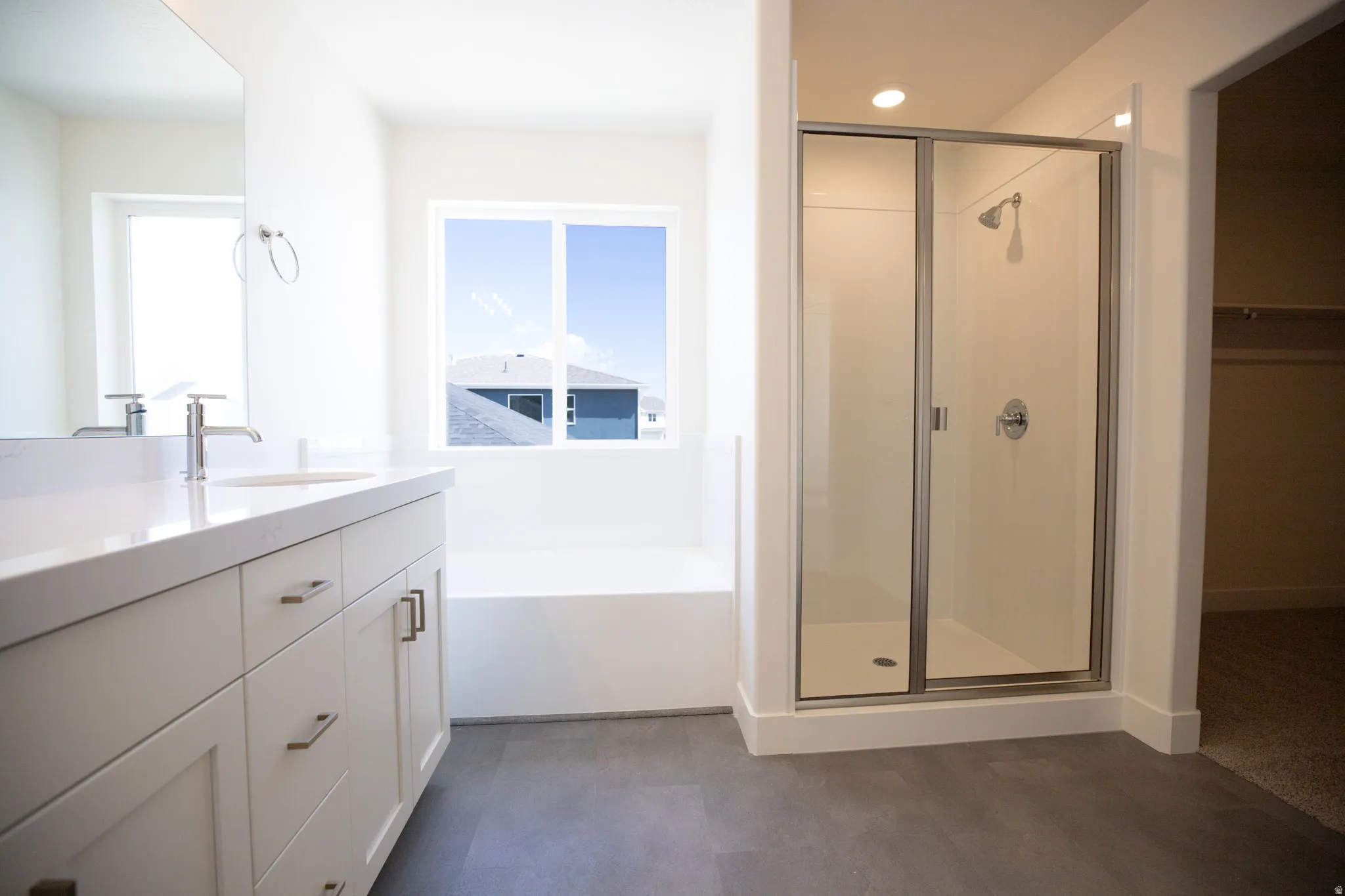 Primary bath with dual sinks, painted wood cabinets, quartz slab countertops, soaker tub and walk-in shower.