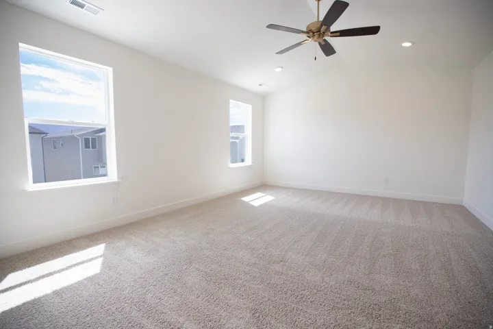 Primary bedroom with vaulted ceiling and ceiling fan.