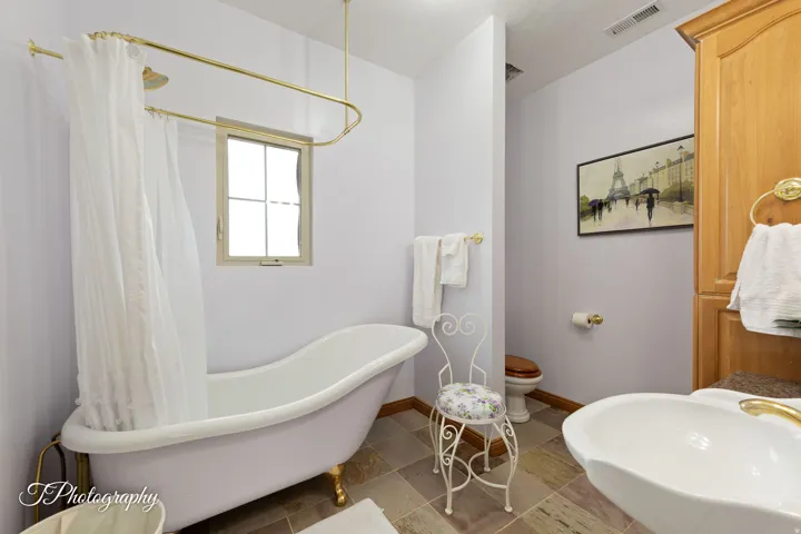 Clawfoot bathtub with an overhead shower fixture and brass hardware