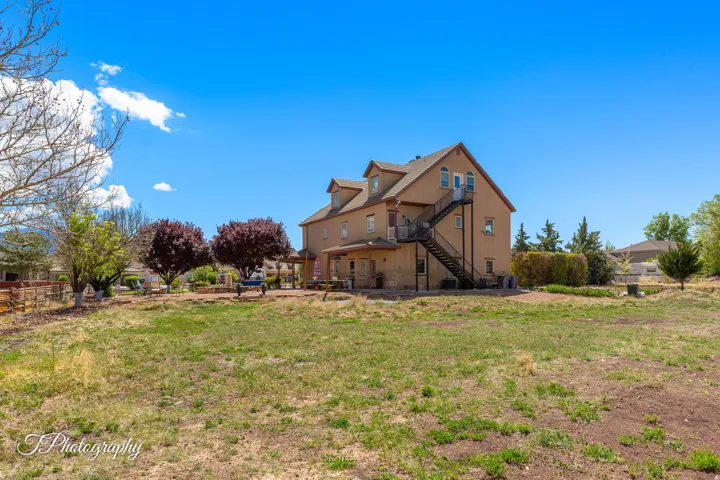 Expansive exterior featuring a stucco facade, multiple dormer windows, an external staircase, and a covered patio