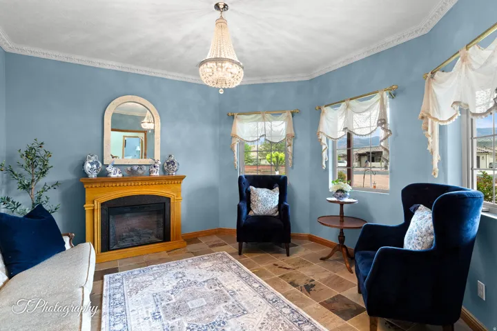 Recessed fireplace with a wood mantel, crown molding, a crystal chandelier, and tiled flooring