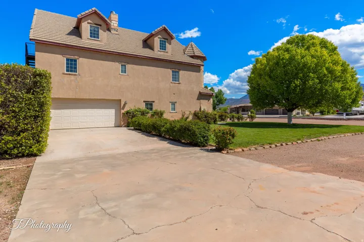 Stucco exterior featuring a multi-car garage, dormer windows, a turret element, and a tile roof