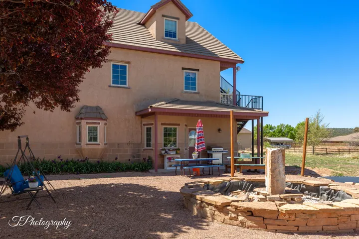 Stucco exterior with a tiled roof, second-story balcony with metal railing, covered patio, and a stone-built pond