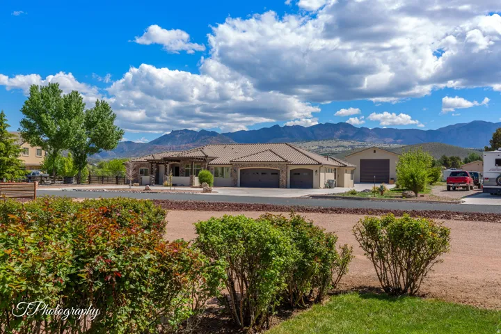 Expansive single-story residence with multiple garage bays and covered carport, situated on substantial acreage with mature landscaping and native desert shrubs