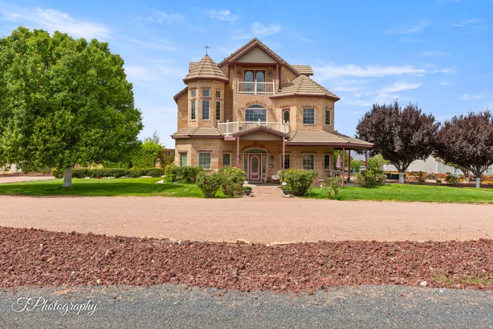 Two-story stucco exterior with stone accents, turret-style architectural features, multiple balconies, and a covered front entry