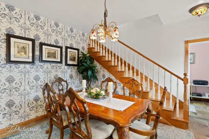 Elegant dining room showcasing classic toile wallpaper, wood-finish flooring, and a wooden dining table with coordinating chairs
