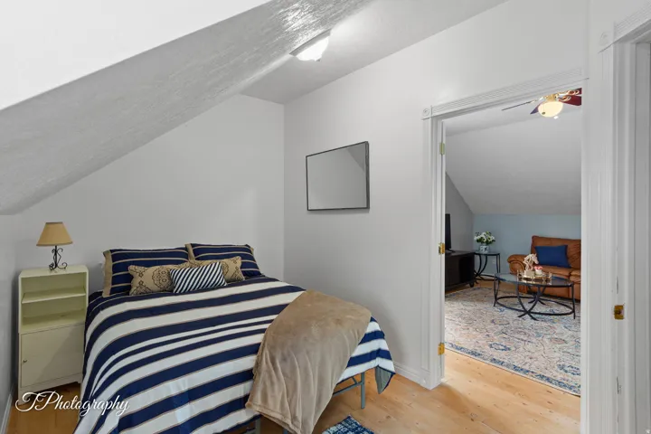 Sloped ceiling architecture with recessed lighting, wood-finish flooring, and white trim