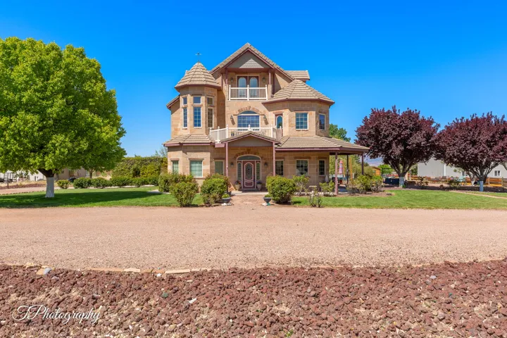 Stone exterior with multiple windows, a second-story balcony with white railing, and an inviting covered porch