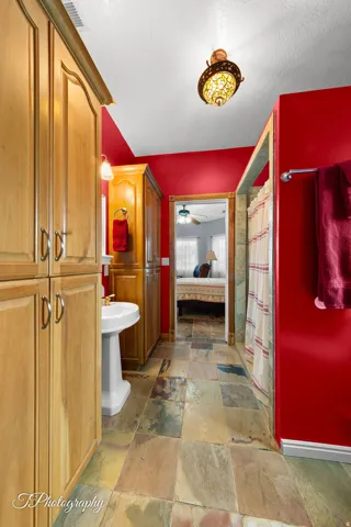 Pedestal sink, wood-finish cabinetry, tile flooring, and overhead lighting fixture