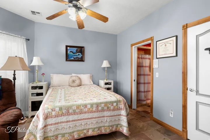 Serene bedroom retreat featuring soft periwinkle walls, wood-trim framing around doorways and closet, ceiling fan with integrated lighting, hardwood flooring, and dual nightstands with task lamps flanking the bed