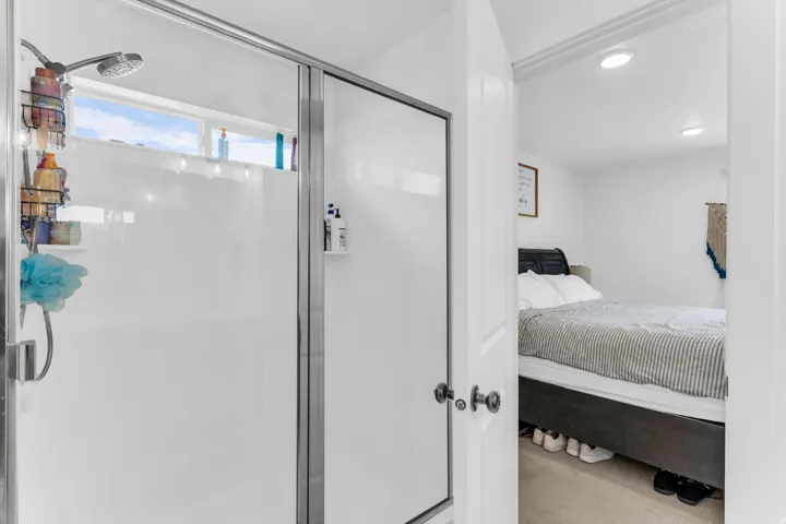 Shower enclosure with clear glass door, chrome fixtures, and a transom window