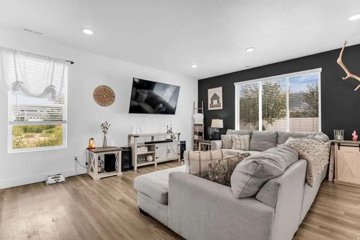 Recessed lighting, wood-finish flooring, white walls, dark accent wall, and a large sliding glass door