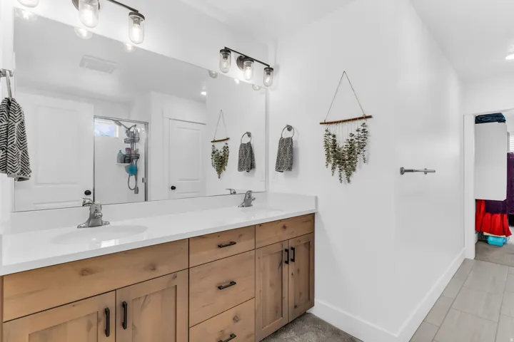 Dual vanity with white countertops, integrated sinks, and wood-finish cabinetry