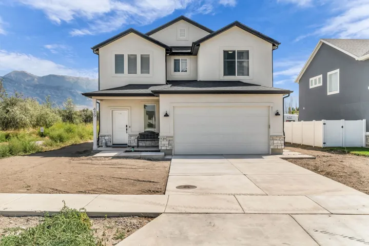 Contemporary two-story exterior with a two-car garage, white stucco siding, and stone accents