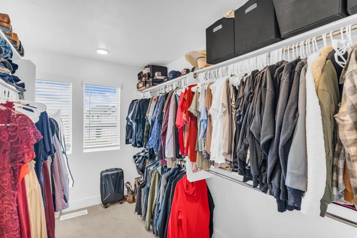 Walk-in closet with recessed lighting, two windows, wall-mounted shelving, and hanging rods