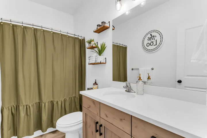 Wood-finish vanity with black hardware, white countertop, and integrated sink
