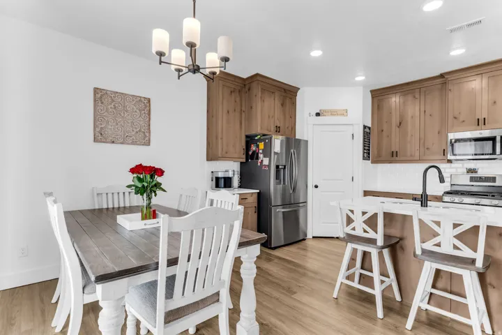 Wood-finish flooring, recessed lighting, and a modern chandelier illuminate the space