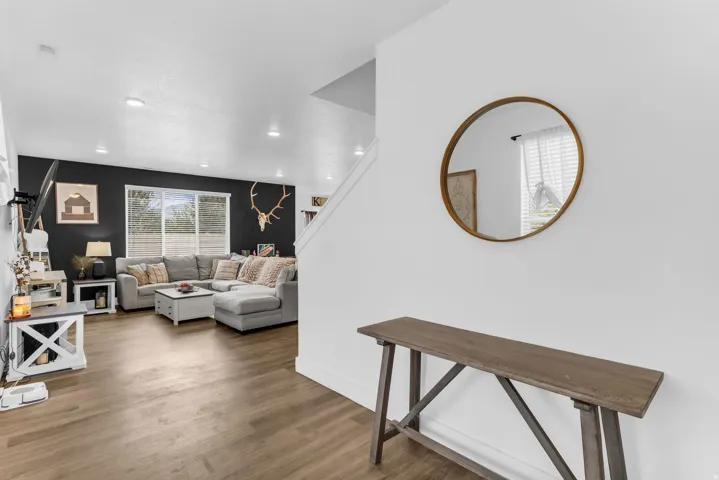 Open-concept living space with wood-finish flooring, recessed lighting, and a prominent window