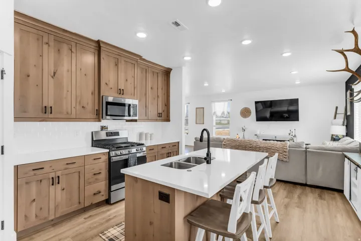 Kitchen featuring wood-finish cabinetry, stainless steel appliances, white subway tile backsplash, and an island with a sink and seating