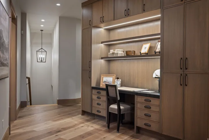Built-in custom cabinetry with integrated desk space, under-shelf lighting, recessed ceiling lighting, wood-finish flooring, and a contemporary hanging light fixture