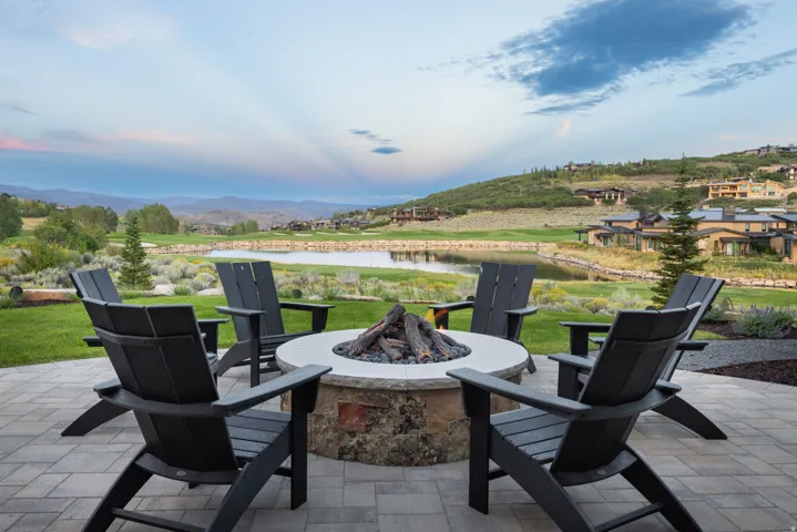 Paver patio featuring a built-in fire pit, surrounded by a manicured lawn