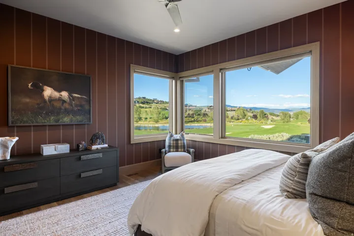 Expansive windows with light wood-finish trim, wood-finish flooring, and a ceiling fan