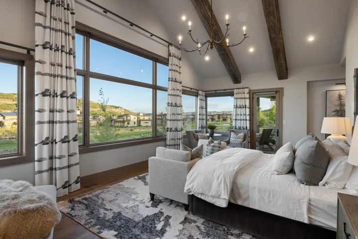 Vaulted ceiling with exposed wood beams, large windows, recessed lighting, and a chandelier