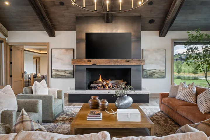 Living area featuring a stone fireplace with a wood mantel, exposed ceiling beams, and wood-finish flooring