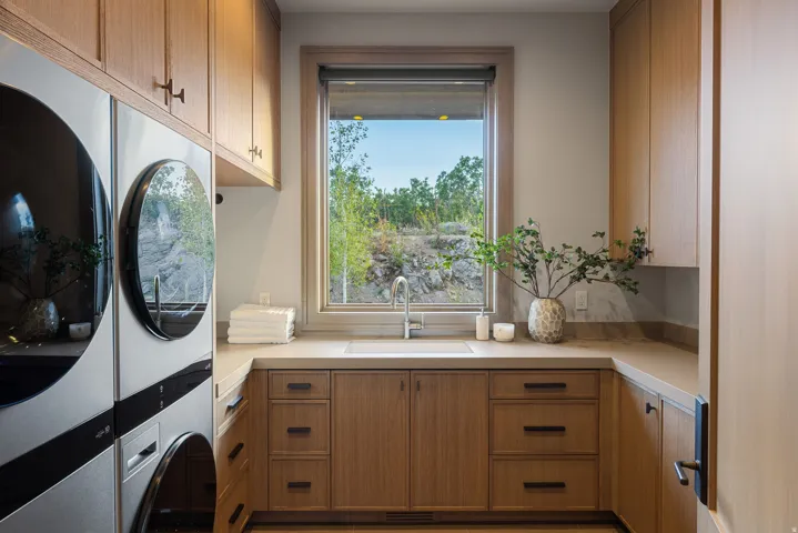 Wood-finish cabinetry with dark hardware, a single basin sink with a chrome faucet, and integrated countertop space