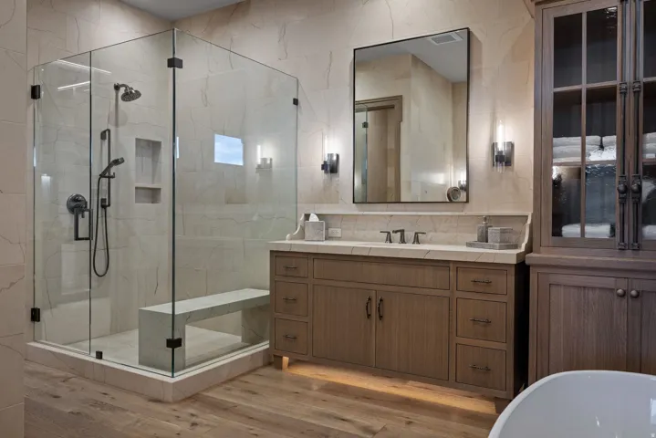 Glass-enclosed shower with a built-in bench, dual shower heads, and integrated shelving
