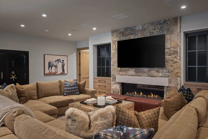 Stone accent wall with a linear gas fireplace and integrated television